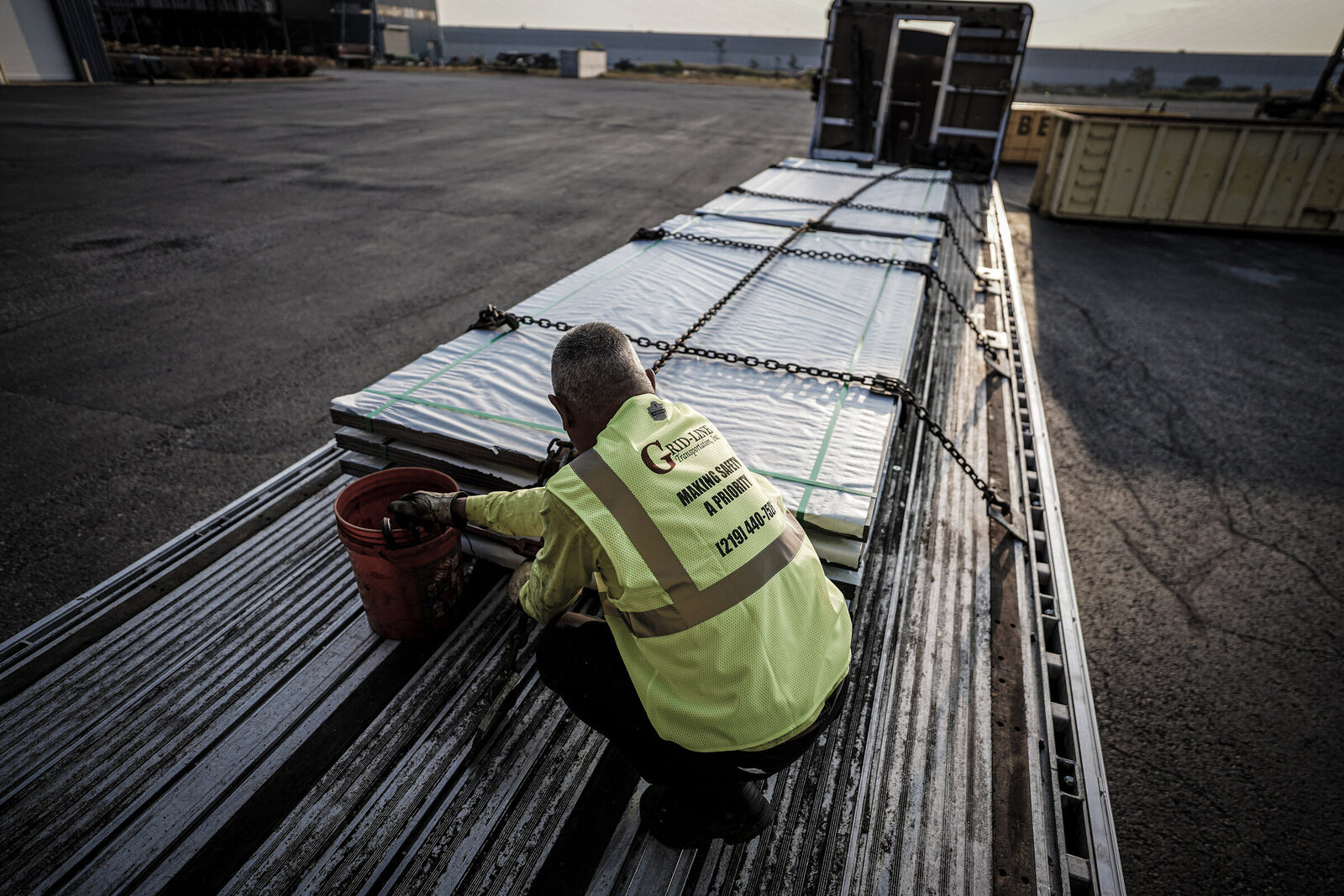 Grid-Line driver tarping a flatbed load at dawn