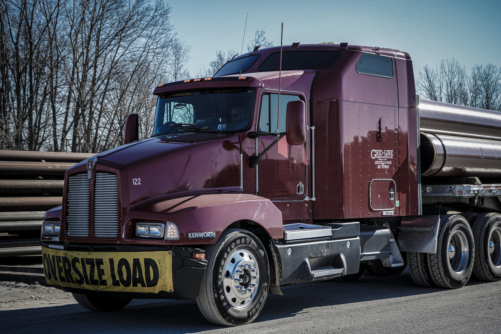 Grid-Line Kenworth tractor staged with an oversize-load banner
